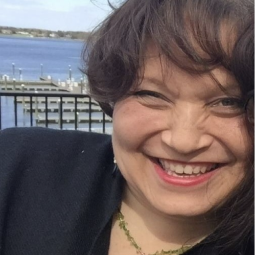 Woman smiling wearing black jacket and necklace