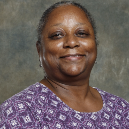Woman grinning wearing purple patterned shirt.