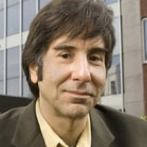 Man grinning wearing yellow button down shirt and brown suit jacket.