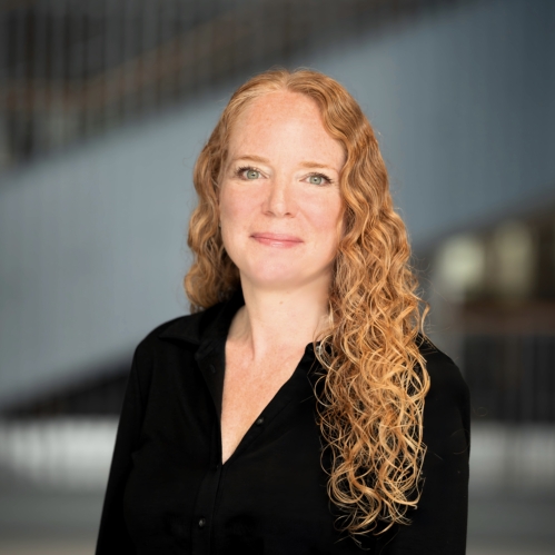 woman with long wavy hair grinning wearing black shirt