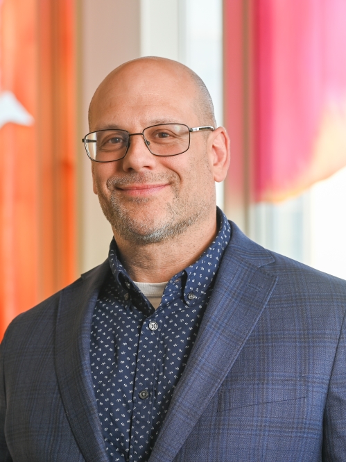 a bald man with a beard and glasses smiling