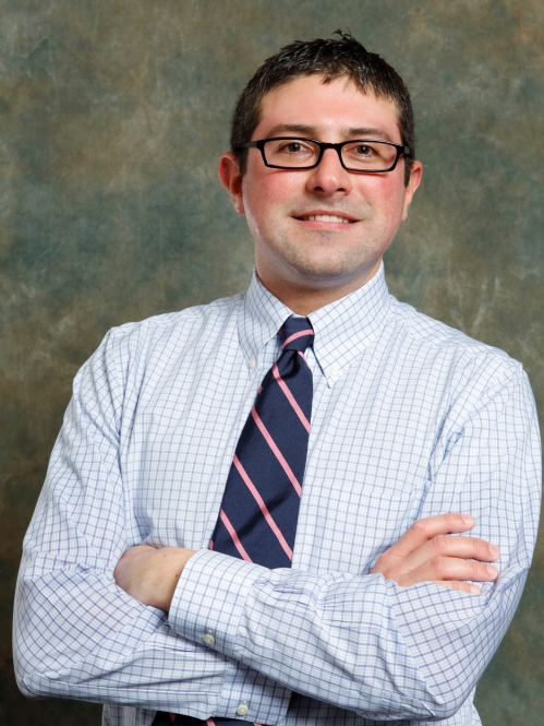 man wearing glasses smiling with arms folded