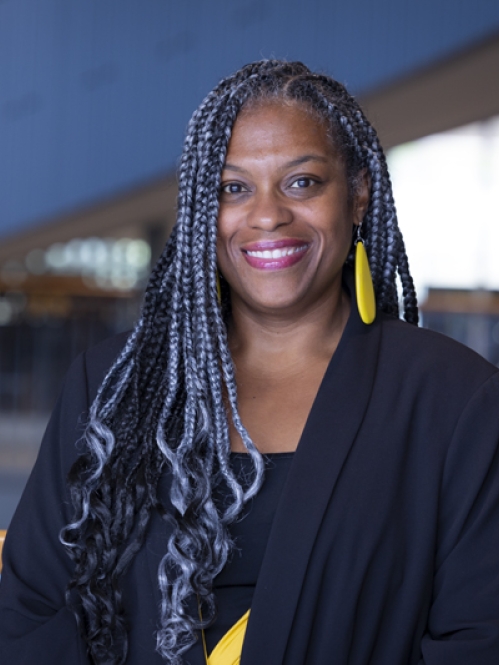 woman in black blazer and gray braids smiling