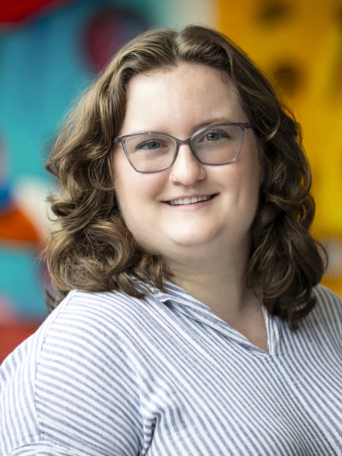 woman wearing glasses and smiling in front of blurred art photo