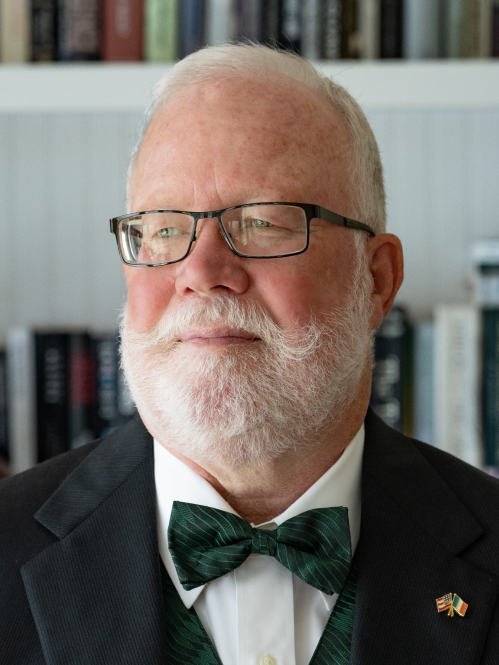 bearded man with glasses and bowtie staring left