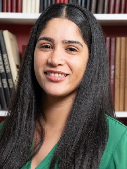 woman with long hair smiling in front of bookcase