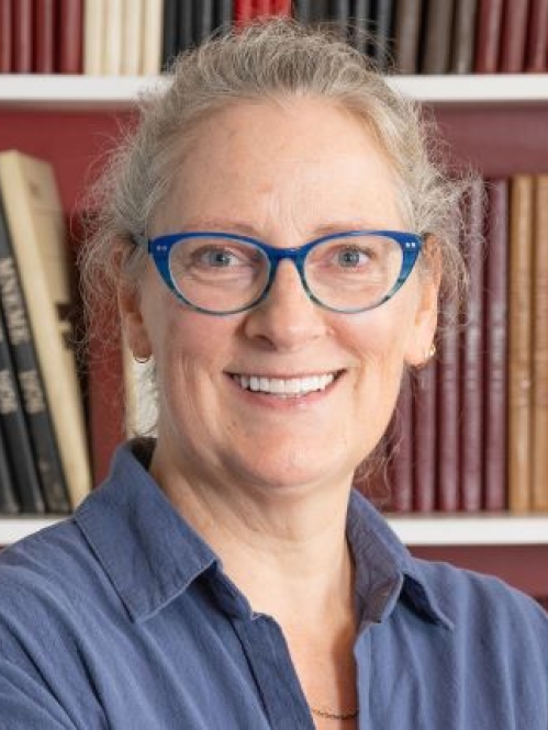 woman in blue glasses smiling in front of bookcase