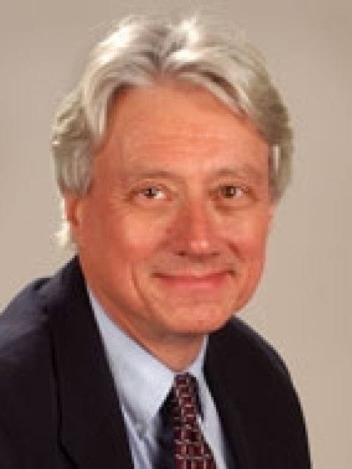 Man grinning wearing blue button down, suit jacket, and tie