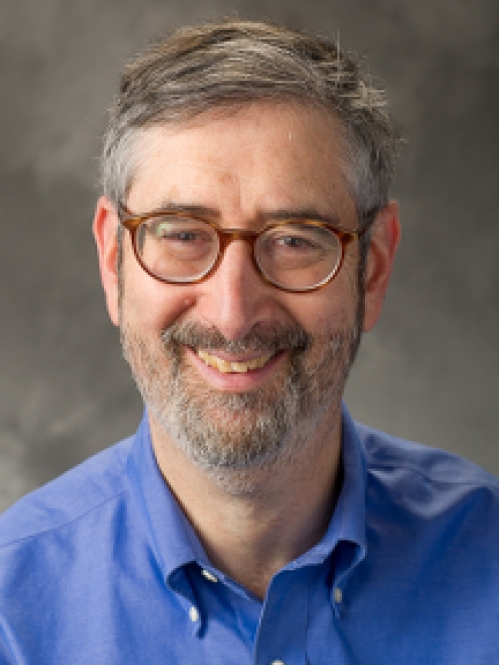 Man smiling wearing glasses and a blue button down shirt