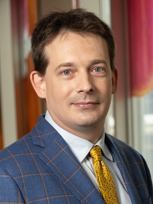 Man grinning with yellow tie and blue suit with yellow stripes 