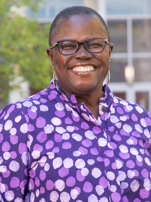 Woman smiling with glasses wearing a purple shirt