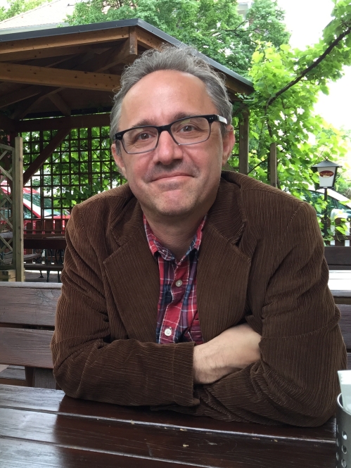 Man grinning wearing glasses and multicolored shirt