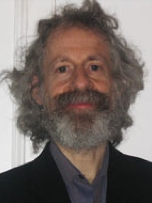 Man grinning wearing grey shirt and black suit jacket