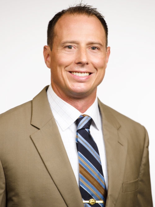 Man smiling wearing white button down, striped tie, and tan suit