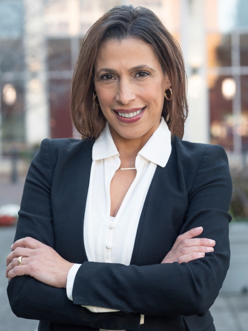 Woman smiling with white collared shirt, black suit jacket, with crossed arms 