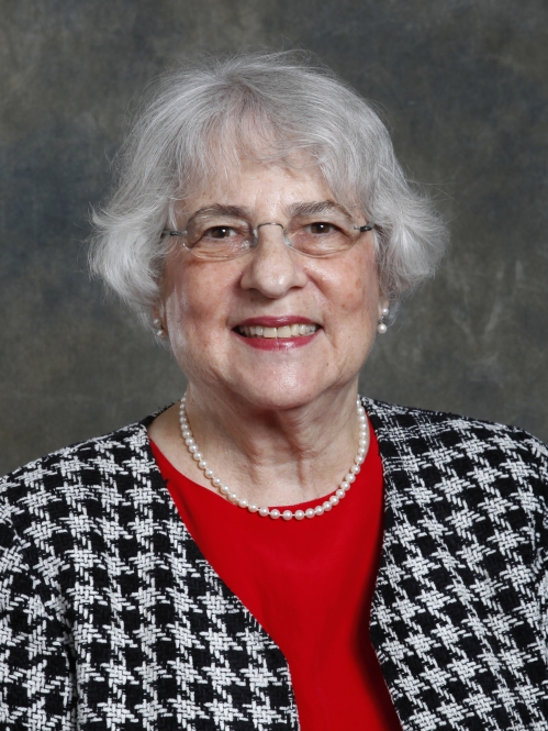 Woman smiling with glasses, red shirt, and black and white houndstooth jacket