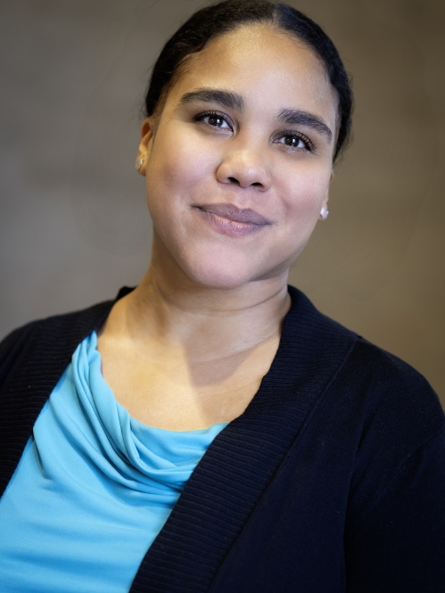 woman in black blazer and blue shirt grinning