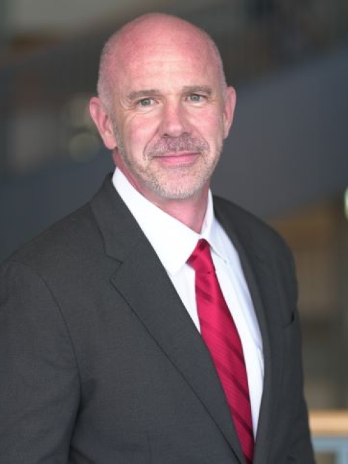 man in black suit and red tie looking ahead