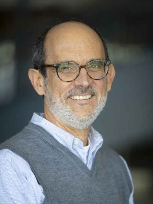 man with gray sweater and blue shirt wearing glasses