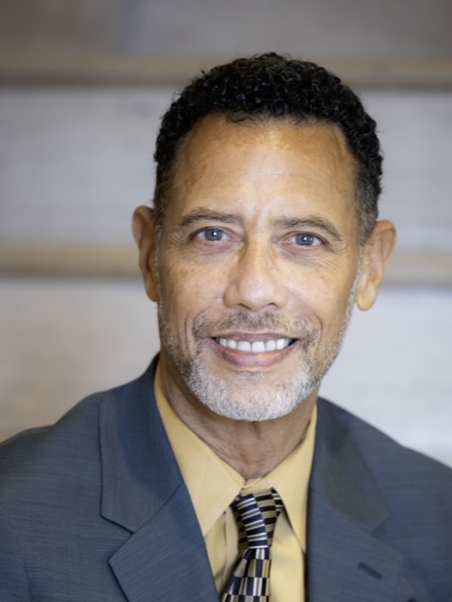 Man in blue suit smiling and sitting on stairs