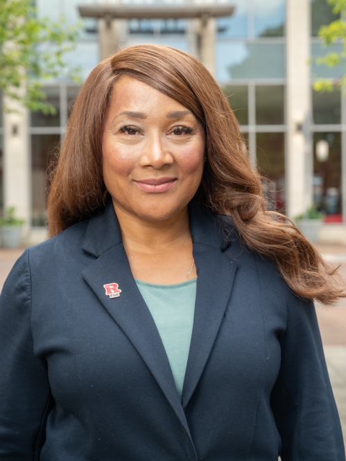 Woman in dark blazer with R Law red pin smiling outside law school