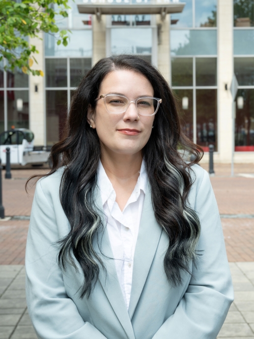 Woman with long dark hair and glasses wearing a light blue blazer