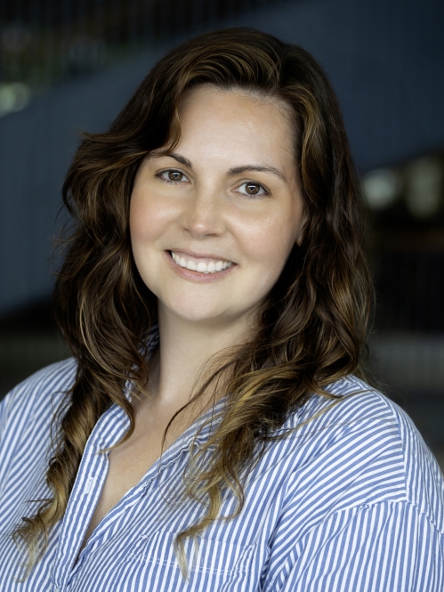 Woman smiling wearing blue and white striped button down shirt.