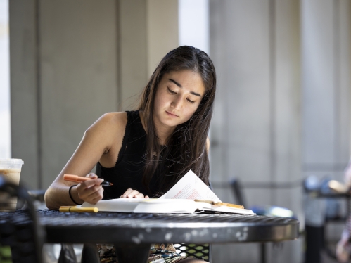 Woman sitting at table and highlighting a book