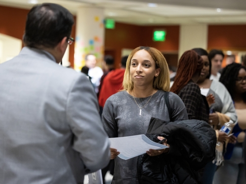 Man talking to woman holding paper 
