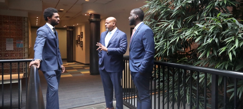 Three men in blue suits standing and talking