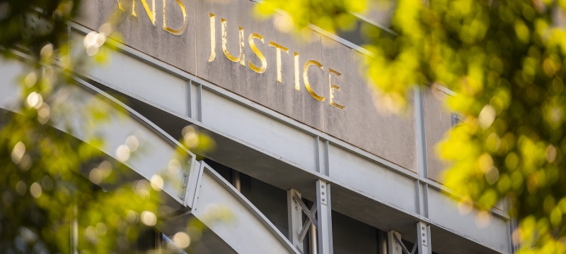 A close-up of the word "Justice" engraved on an exterior of a building at Rutgers Law School.