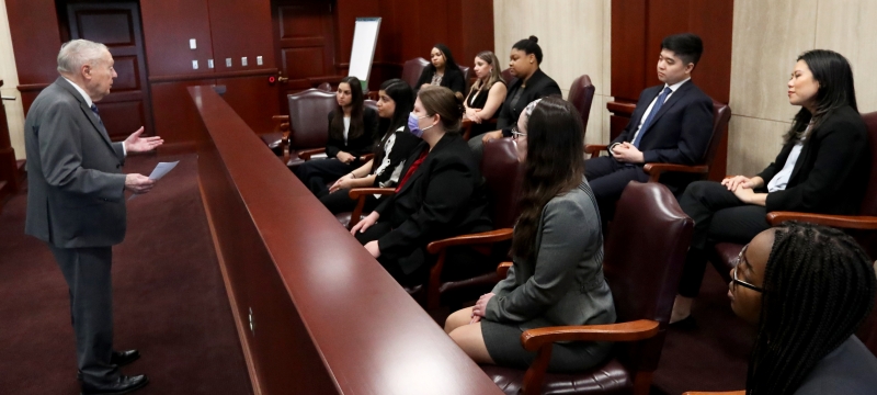 judge talking to students seated in jury box in courtroom