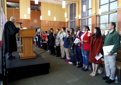 people standing and taking an oath from a person behind a podium