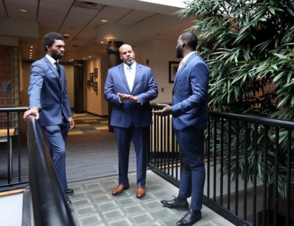 three men in suits standing and conversing with one another