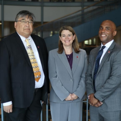 three people in suits posing for a photograph