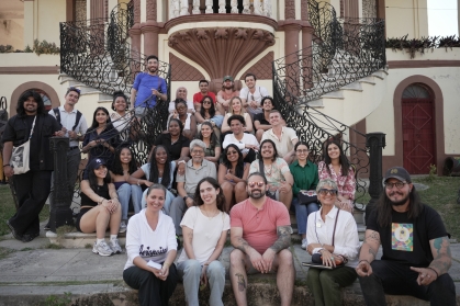 group of people seated on front building stairs and smiling
