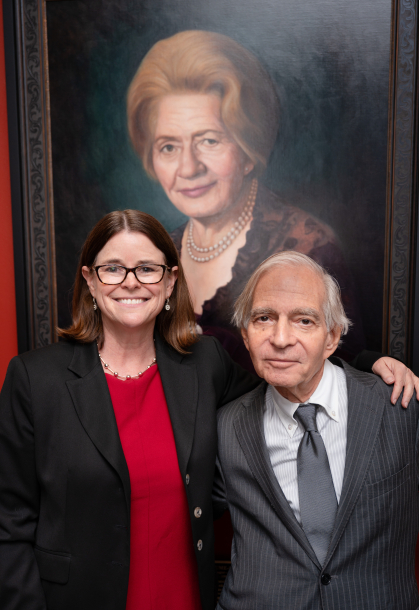 woman and man standing in front of portrait of a woman