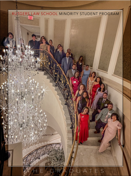 two rows of people standing on spiral staircase next to large crystal chandelier looking up and smiling in formal wear