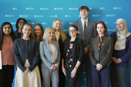 A group of students posing together in front of a United Nations Human Rights step-and-repeat backdrop.