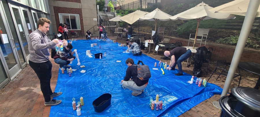 Students tie-dying shirts on large blue tarp