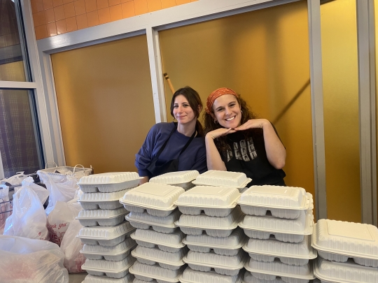 Two female students near stacks of packed lunches.