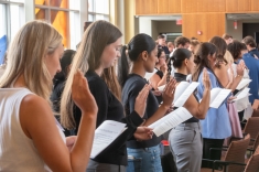 women students raising hands and reading from papers