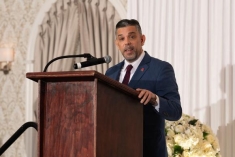 man in a suit speaking behind a podium