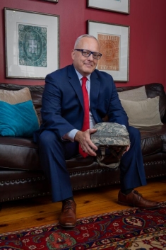 man in a suit holding a military helmet and posing for a photograph