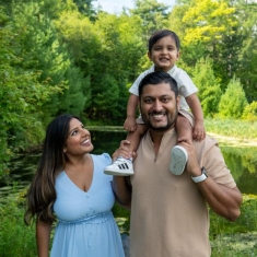 photograph of a family standing in front of greenery