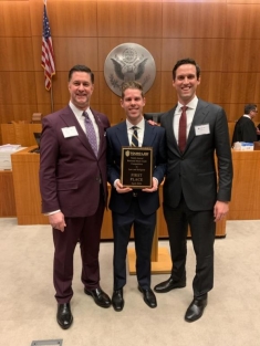 Group of men in suits posing for a photograph with an award
