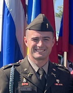man smiling in U.S. National Guard uniform in front of flags