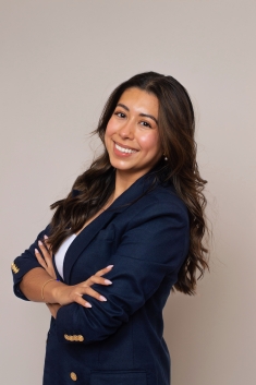 woman in navy blazer smiling with arms folded