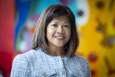 woman smiling in front of blurred art mural