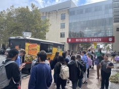 Group of people standing in front of a food truck and a building